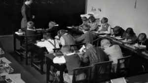 Historyczna fotografia przedstawiająca uczniów w klasie przy tablicy w 1935 roku.