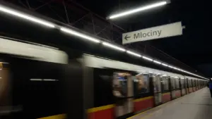 Pociąg wjeżdżający na stację metra w Warszawie z widocznym znakiem kierunku Młociny.
