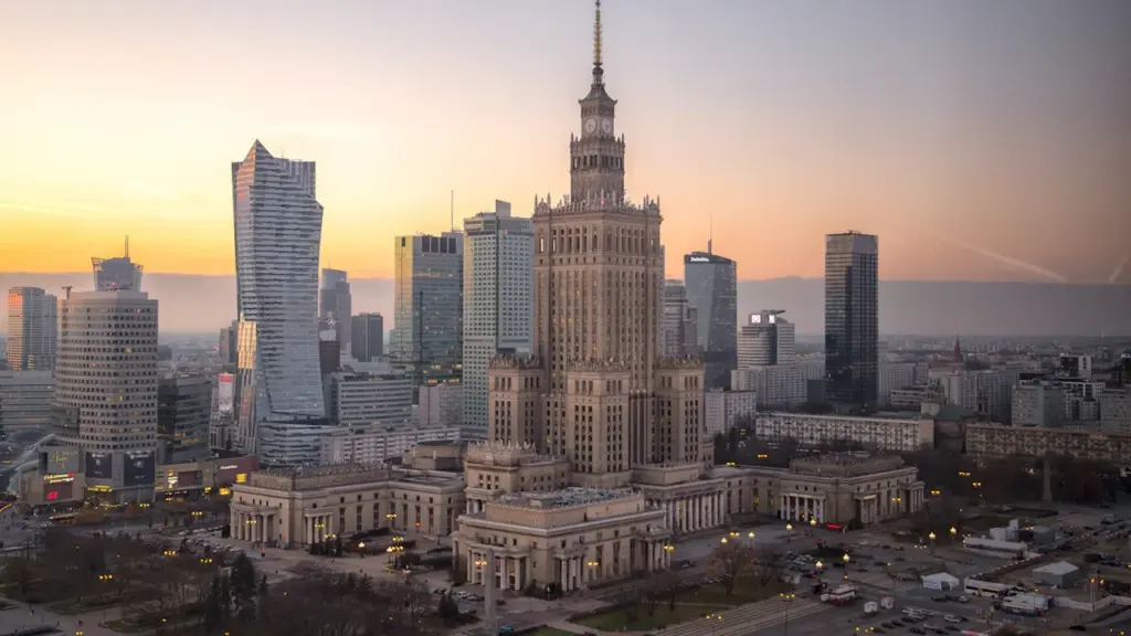Panoramatyczny widok na centrum Warszawy z Pałacem Kultury i Nauki o zachodzie słońca.