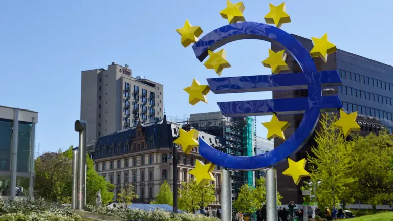 Symbol euro z gwiazdami unijnymi przed budynkami instytucji finansowych w Europie.