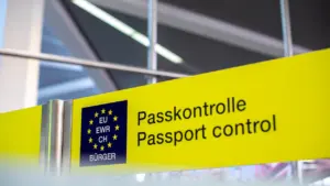 Żółty znak informacyjny z napisem kontrola paszportowa w języku niemieckim i angielskim.