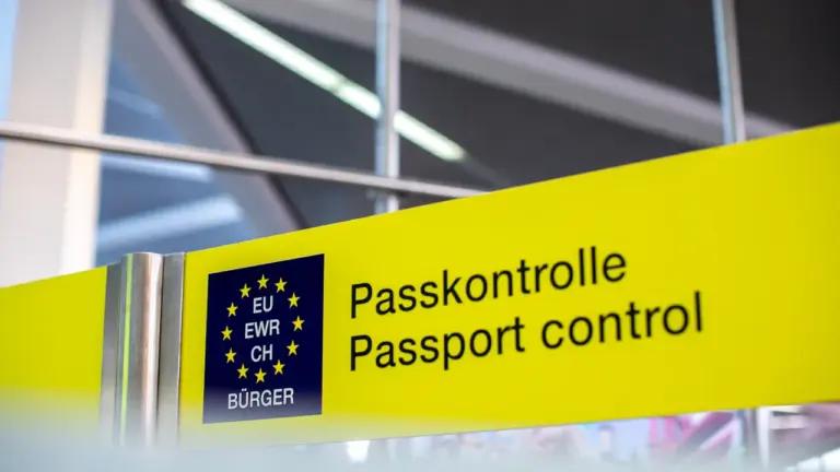 Żółty znak informacyjny z napisem kontrola paszportowa w języku niemieckim i angielskim.