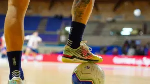 Zawodnik futsalu z piłką przy nodze na hali sportowej przed meczem ligowym.